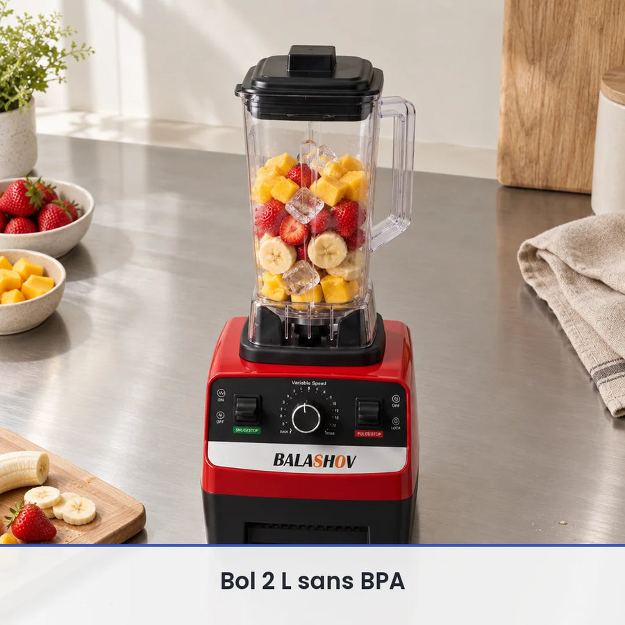 Bol de 2 L du blender BALASHOV 2000W rempli aux deux tiers de fraises, mangue, banane et glaçons, sur un plan inox