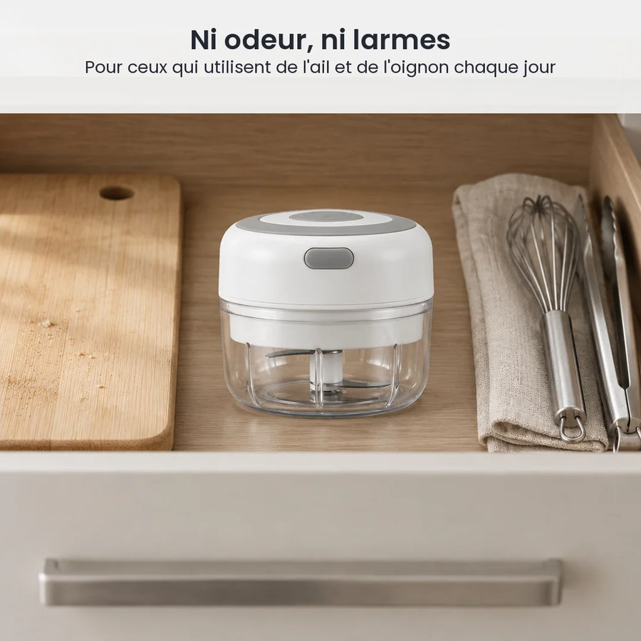 Mini hachoir électrique blanc 100 ml rangé dans un tiroir de cuisine en bois clair, à côté d'ustensiles et d'une planche