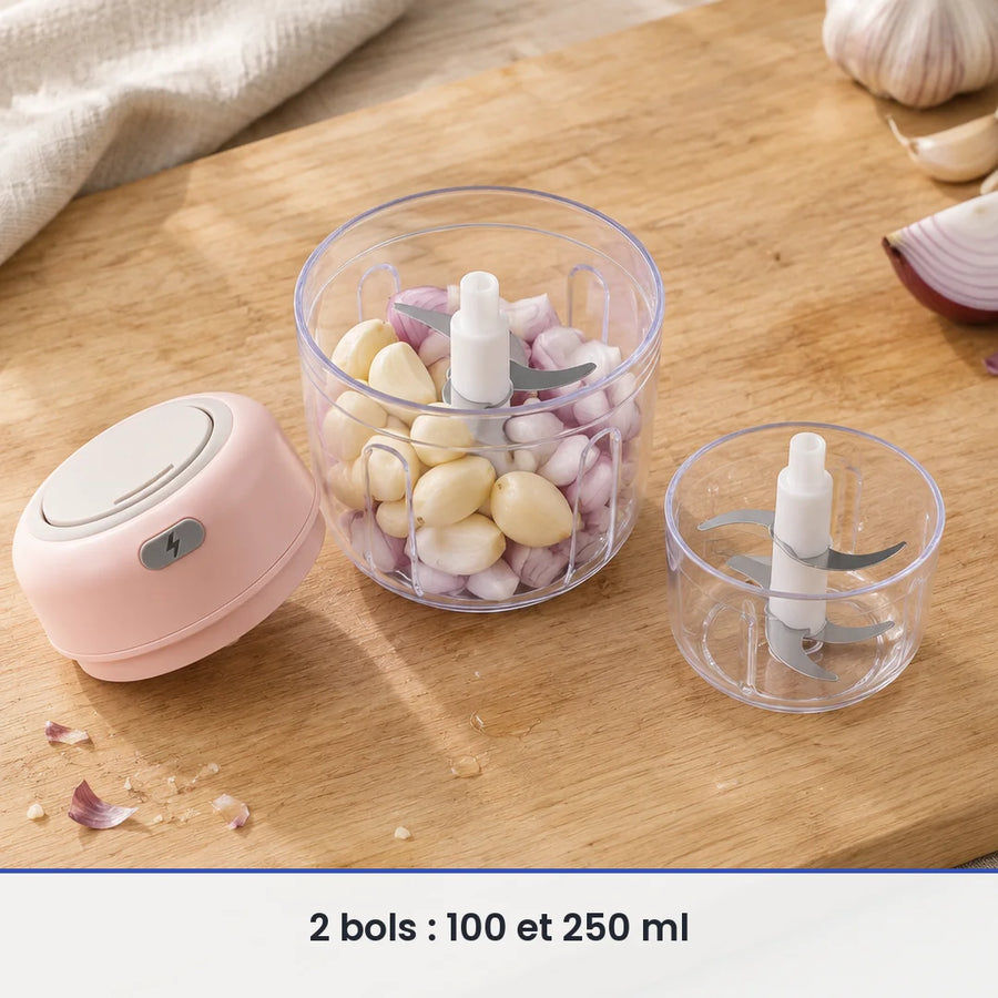 Bol de 250 ml du mini hachoir rose rempli d'ail et d'échalote, couvercle-moteur rose et bol de 100 ml posés à côté