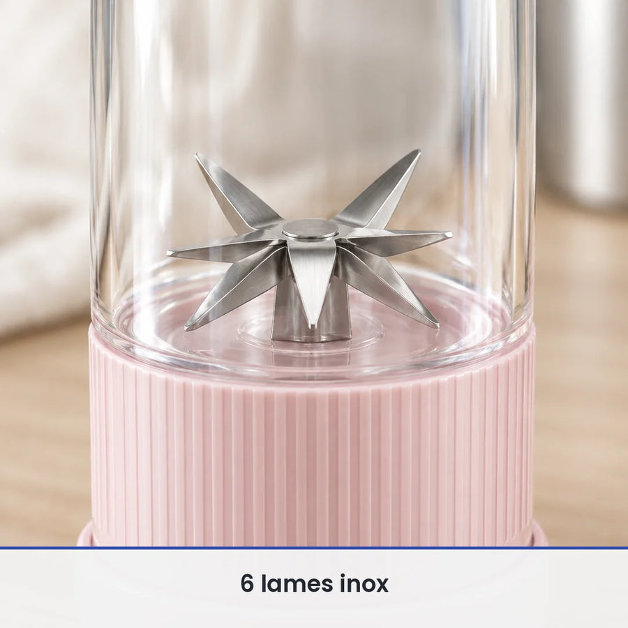 Gros plan sur les 6 lames inox en étoile du blender bouteille rose, vues à travers la paroi de la bouteille transparente