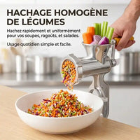 Performance de Hachage de Légumes : Plan rapproché du hachoir manuel (modèle #8, manche bois) en train de hacher une variété de légumes (carottes, céleri, oignons) pour obtenir une brunoise uniforme qui tombe dans un bol blanc. Texte : « HACHAGE HOMOGÈNE DE LÉGUMES »