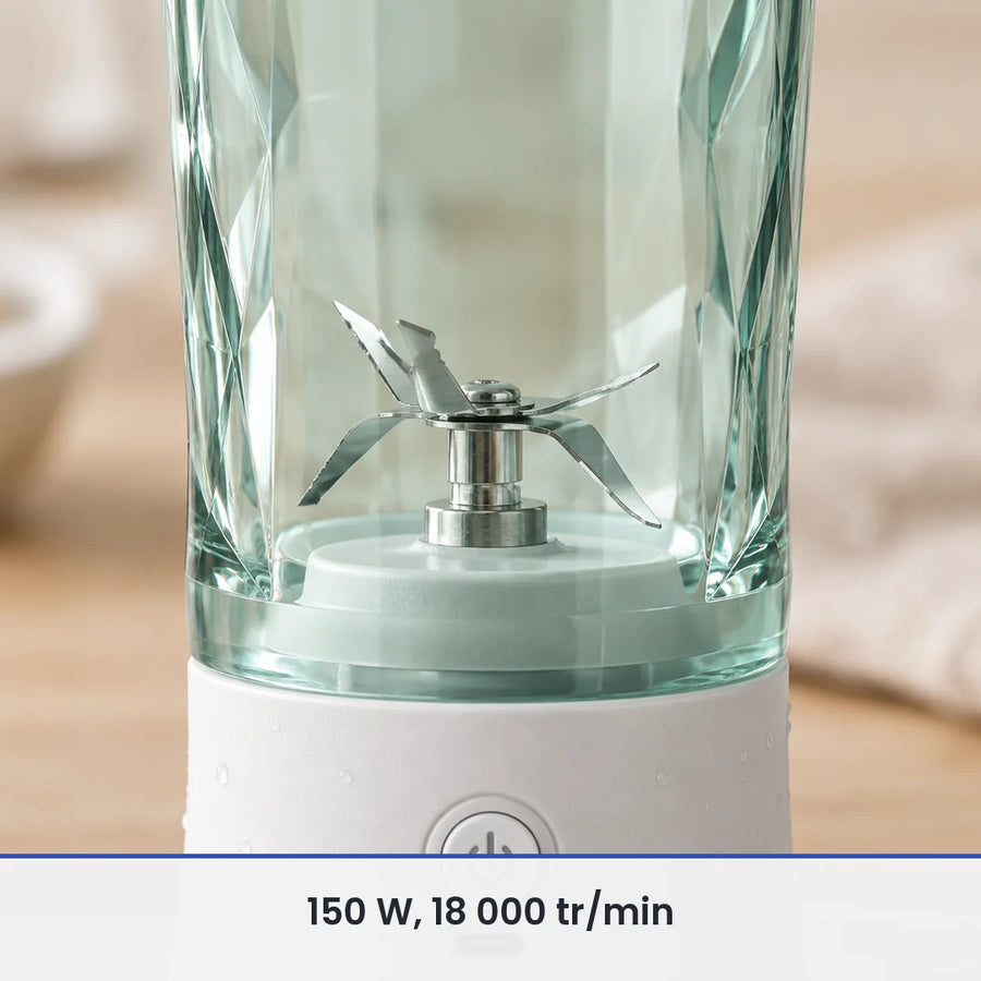 Gros plan sur les lames inox du blender portable blanc 600 ml, vues à travers le gobelet vert d'eau transparent