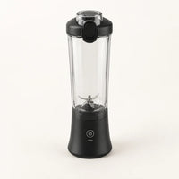 Blender portable 600 ml noir avec gobelet transparent à facettes et couvercle noir à clapet, sur fond blanc cassé