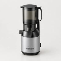 Extracteur de jus BioloMix argenté et noir avec grande trémie transparente fumée à poignée, sur fond blanc cassé