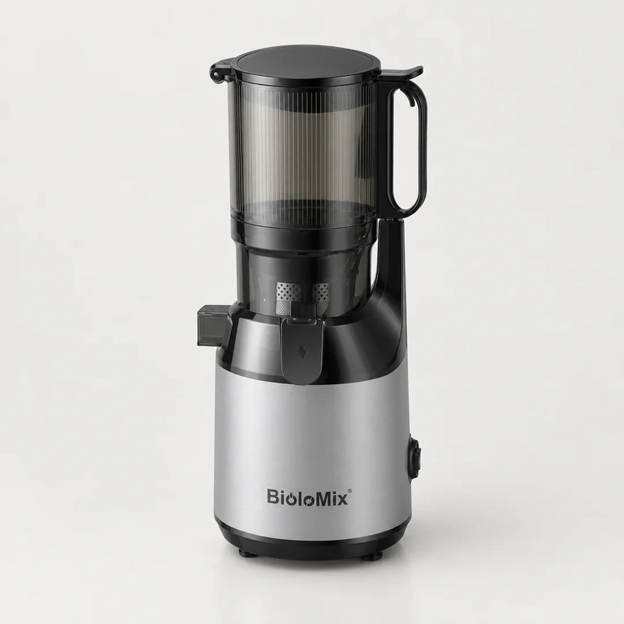 Extracteur de jus BioloMix argenté et noir avec grande trémie transparente fumée à poignée, sur fond blanc cassé
