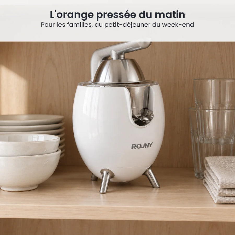 Presse-agrumes électrique ROUNY blanc rangé dans un placard de cuisine en bois clair, à côté de bols et de verres