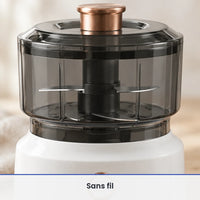 Gros plan sur les lames inox du hachoir électrique 350 ml blanc, vues à travers le bol gris fumé fermé par son couvercle