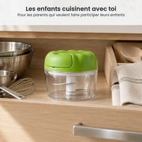 Hachoir manuel à ficelle compact vert pomme rangé dans un tiroir de cuisine familiale, à côté de bols inox et d'un fouet