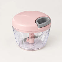 Hachoir manuel à ficelle 500 ml avec couvercle rose poudré, poignée de tirage grise et bol transparent, sur fond blanc cassé