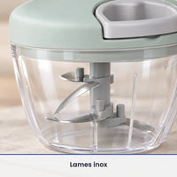 Gros plan sur les lames inox fixées sur l'axe gris du hachoir à ficelle vert menthe, vues à travers le bol transparent