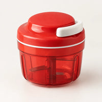 Hachoir manuel à ficelle compact rouge avec poignée de tirage blanche et bol rouge translucide, sur fond blanc cassé