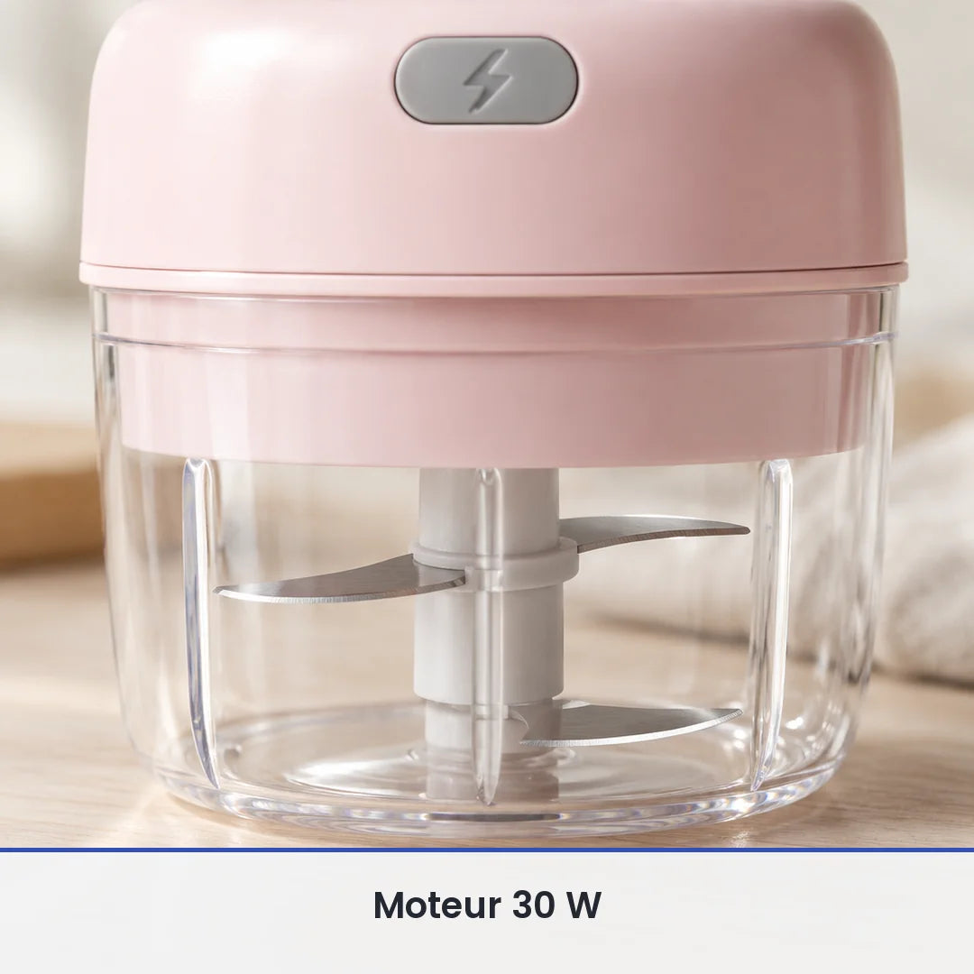 Gros plan sur les lames inox du mini hachoir électrique rose, vues à travers la paroi du bol transparent de 100 ml fermé
