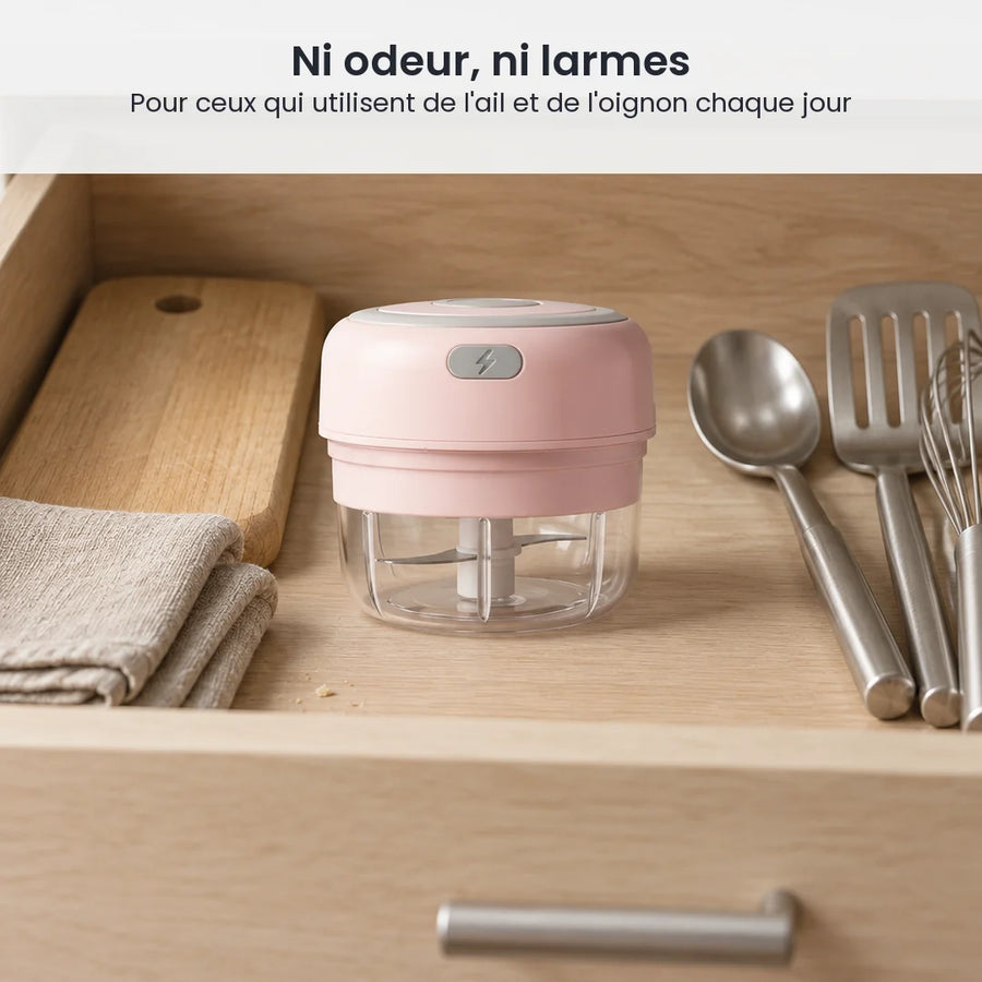 Mini hachoir électrique rose poudré 100 ml rangé dans un tiroir de cuisine en bois clair, à côté de couverts et d'une planche