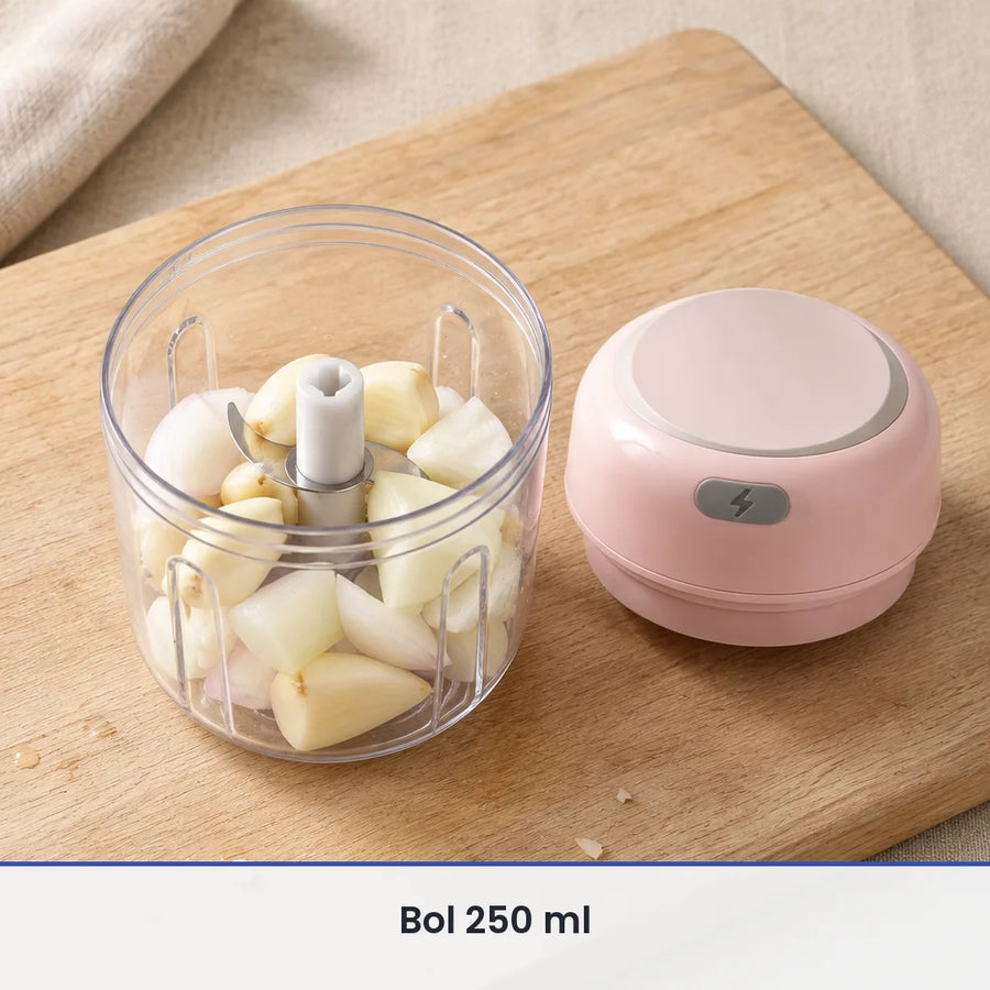 Bol transparent de 250 ml du mini hachoir électrique rose rempli d'ail et d'oignon, couvercle-moteur rose posé à côté