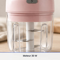 Gros plan sur le couteau inox du mini hachoir électrique rose 250 ml, vu à travers la paroi du bol transparent fermé
