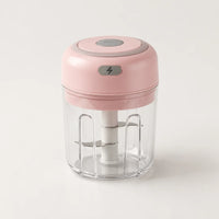 Mini hachoir électrique rose poudré 30 W avec bol transparent de 250 ml et bouton gris à éclair, sur fond blanc cassé