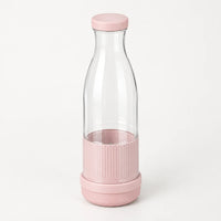 Blender bouteille portable rose poudré avec bouteille transparente au col étroit et base striée rose, sur fond blanc cassé