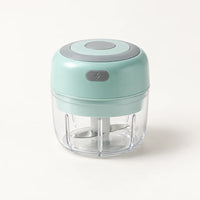 Mini hachoir électrique vert menthe 30 W avec bol transparent de 100 ml et bouton gris à éclair, sur fond blanc cassé