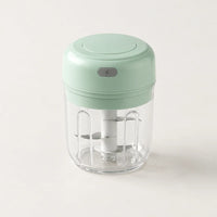 Mini hachoir électrique vert menthe 30 W avec bol transparent de 250 ml et bouton gris à éclair, sur fond blanc cassé