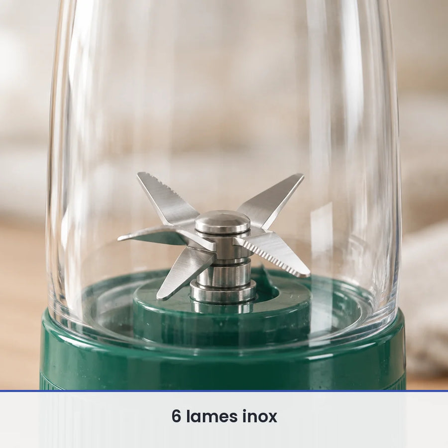Gros plan sur les 6 lames inox du blender bouteille vert sapin, vues à travers la paroi de la bouteille transparente