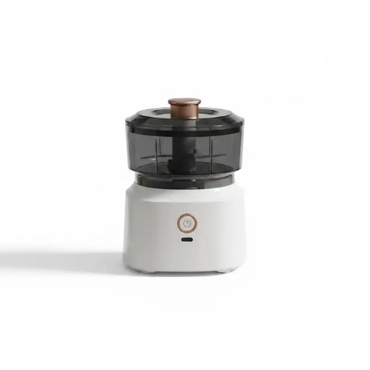 Mini hachoir électrique compact blanc avec bol transparent fumé et bouton poussoir cuivré, sur fond blanc