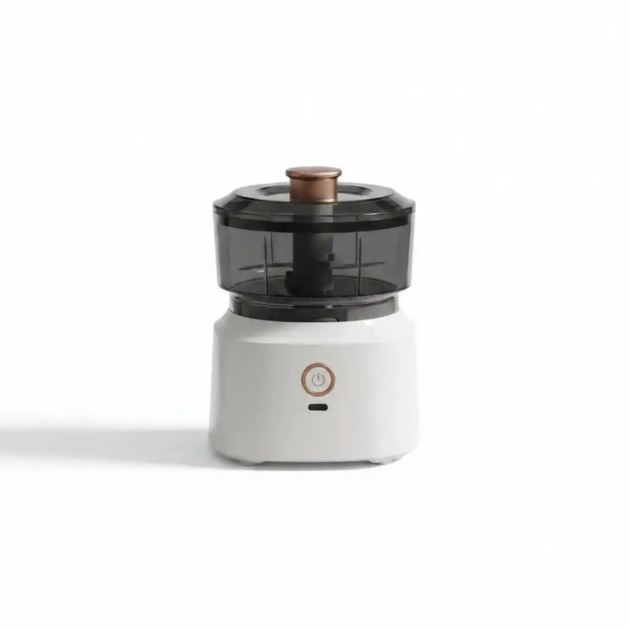 Mini hachoir électrique compact blanc avec bol transparent fumé et bouton poussoir cuivré, sur fond blanc