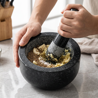 Mortier et pilon en granit massif 16 cm noir, en cours d'utilisation